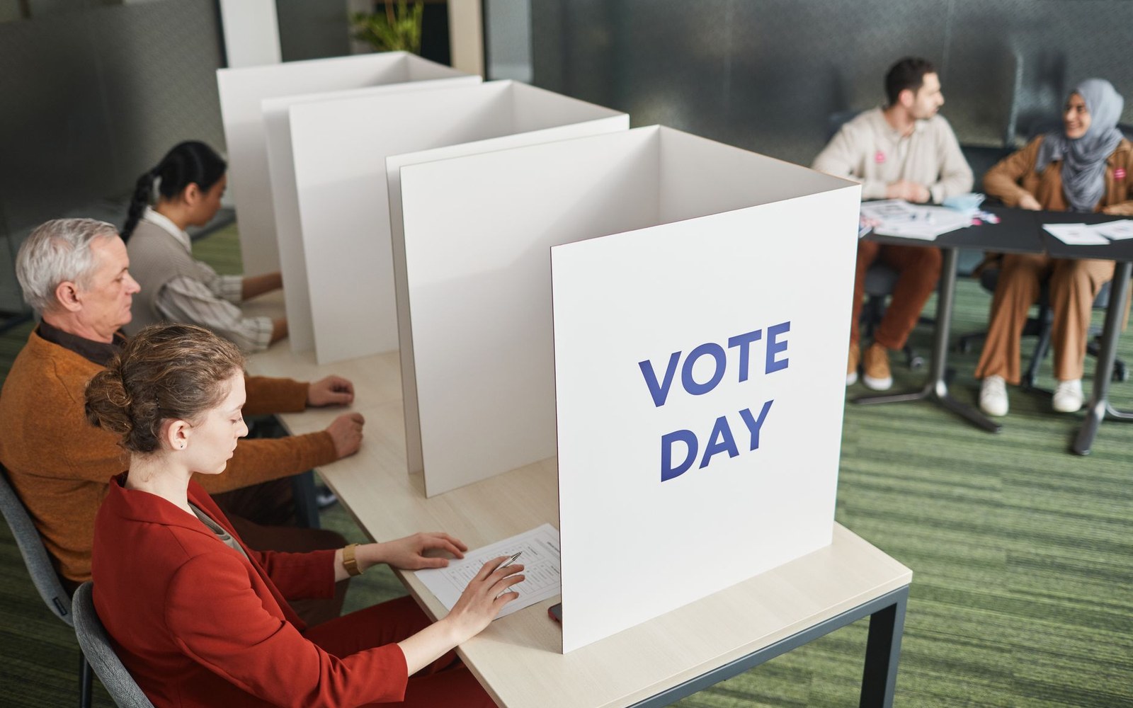 Hands folding a paper ballot at a screened booth