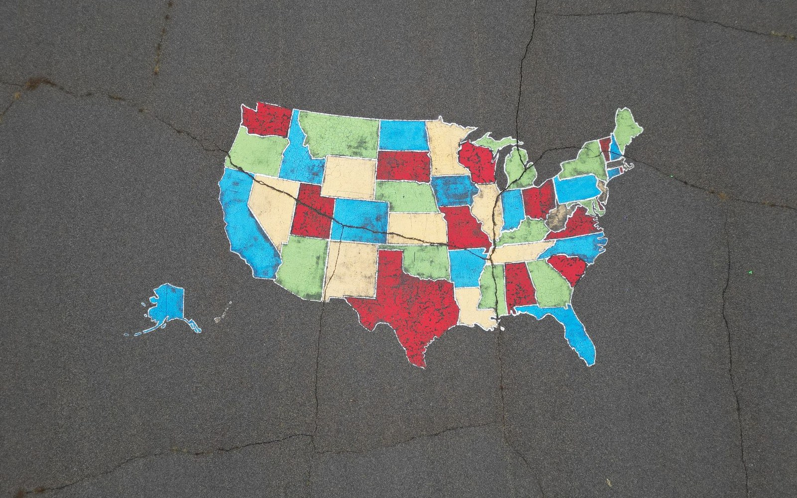 A map of the United States painted on cracked pavement, states colored in red, blue, green and tan